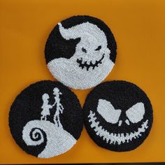 three black and white halloween coasters on a yellow surface