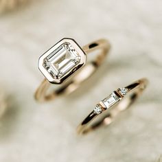 two engagement rings sitting next to each other