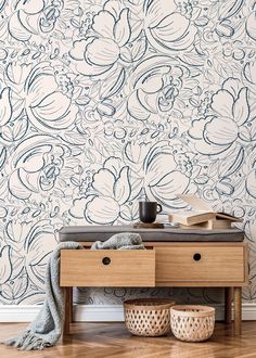 a wooden table with two baskets on it and a wall paper behind it that has blue flowers