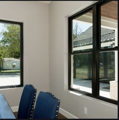 a dining room table with blue chairs next to two large windows