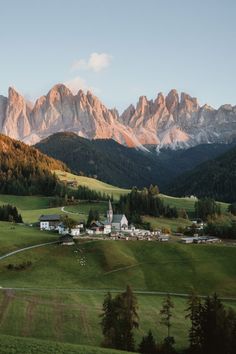 the mountains are covered in green grass and trees, while houses sit on top of them