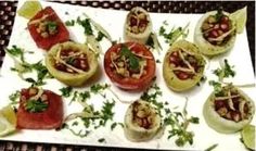 small appetizers are arranged on a plate with garnishes and lime wedges