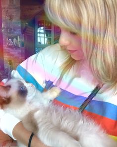 a woman holding a cat in her arms and looking at it's own reflection