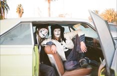 two people sitting in the back seat of a car with their faces painted like skeletons