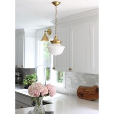 a vase with flowers in it sitting on a kitchen counter top next to a light fixture