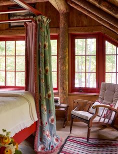 a bed sitting in a bedroom next to two windows with red trimming on them