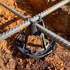 a close up of a metal object on the ground with dirt and rocks in the background