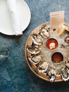 a platter with oysters and sauce on it next to two plates of food