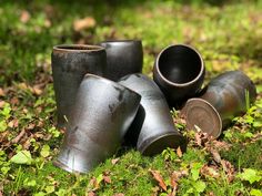 there are many old metal vases on the ground in the grass and one is empty