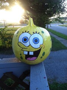 a yellow pumpkin decorated with an image of spongebob on it's face