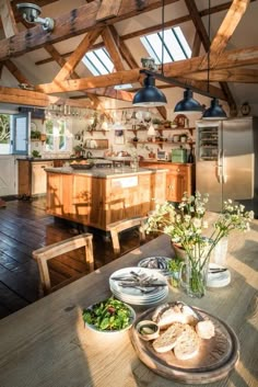 an open kitchen and dining area with wooden beams on the ceiling, along with plates of food