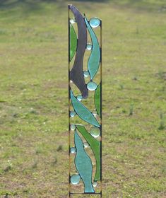 a tall stained glass window sitting on top of a grass covered field