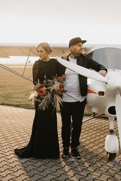 a man and woman standing next to an airplane