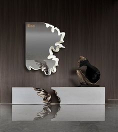 a mirror sitting on top of a table next to a sculpture