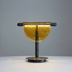 a table lamp that is made out of glass and has a black base with a yellow shade on it