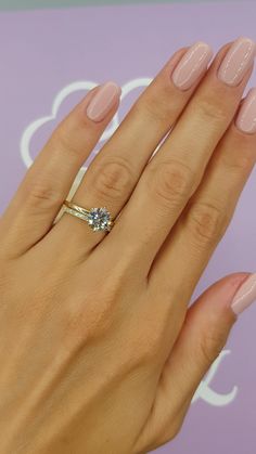 a woman's hand with pink manicured nails and an engagement ring