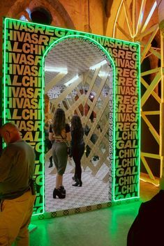 people standing in front of a large mirror with words all over it and on the wall