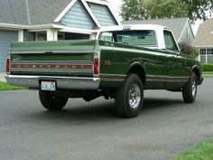 a green pick up truck parked in front of a house