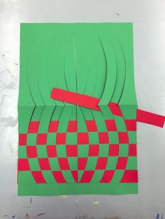 a piece of paper cut out to look like a green and red square with some red strips on it