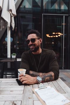 a man sitting at a table with a cup of coffee