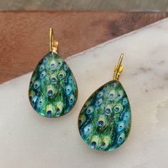 Turquoise And Green Peacock Feather Print. Glass Or Gun Metal Dome. Gold Base. 18x25mm Stone. 2” Drop. Bundle Discounts. Many Styles And Colors To Choose From. 500+ Green Peacock Design Drop Earrings, 90s Earrings, Peacock Feather Print, Green Peacock, Vintage Drop Earrings, Spider Earrings, Bronze Earrings, Crystal Fashion, Ear Cuff Earings