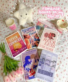 some books are laying on a bed with pink flowers and a stuffed animal next to them