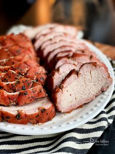 sliced meat on a white plate with black and white striped napkin