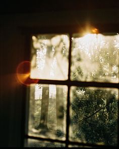 an open window showing trees outside and the sun shining through it's panes