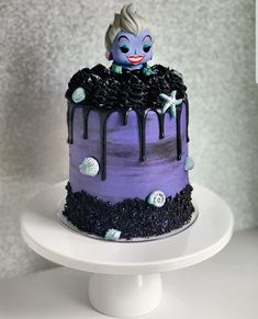 a purple and black cake sitting on top of a white plate