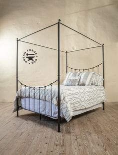 a bedroom with a four poster bed and wooden flooring in front of a white wall