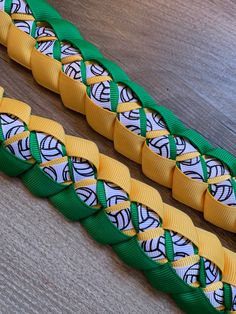 two pieces of green and yellow ribbon sitting on top of a wooden table next to each other