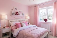 a bedroom decorated in pink and white with pictures on the wall