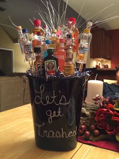 a bucket filled with lots of bottles on top of a table next to a candle