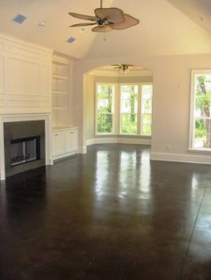 an empty living room with large windows and a ceiling fan in the middle of it