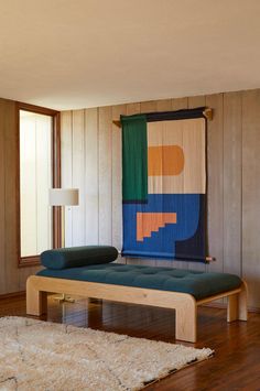 a living room with a couch and rug on the floor next to a wall that has wood paneling