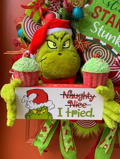 a grinch christmas wreath with cupcakes and a sign that says, mighty nice i tried