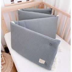 two gray pillows sitting on top of a bed next to a crib in a room