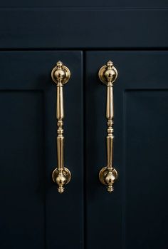 two golden handles on a dark blue cabinet with gold knobs and brass pulls in the middle