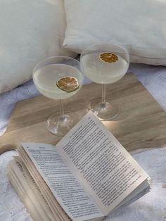 two glasses of wine and an open book on a bed