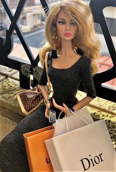 a doll sitting on top of a table holding shopping bags