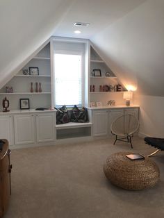 an attic bedroom with built - in bookshelves, shelves and a round ottoman