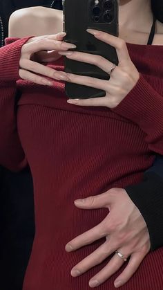 a woman in a red dress is holding her cell phone up to her chest with both hands