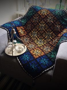 a blanket is sitting on top of a couch next to a cup and saucer