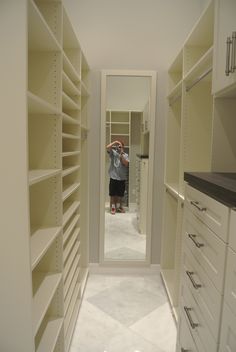 a man taking a photo in the mirror of a walk - in closet with white shelving