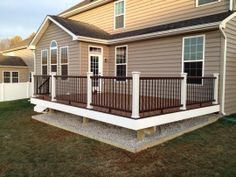 a house with a deck in front of it and a fence around the back yard