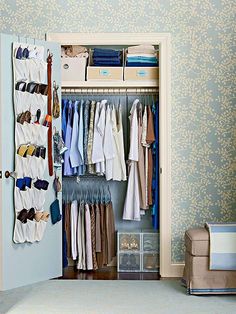 an open closet with clothes and shoes hanging on the wall, next to a chair