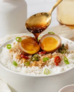 an egg is being drizzled over rice in a bowl with chopsticks