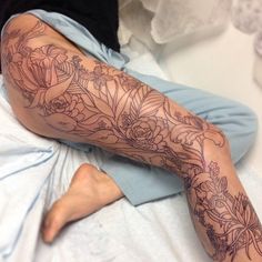 a person laying on a bed with tattoos on their arms and legs, all covered in flowers