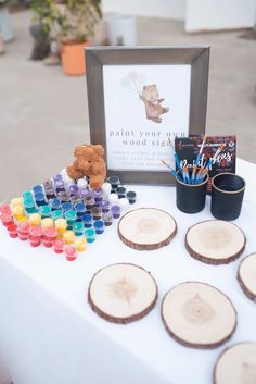 a table topped with lots of wooden slices next to a sign and cupcakes