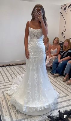 a woman in a white wedding dress is taking a selfie with her cell phone